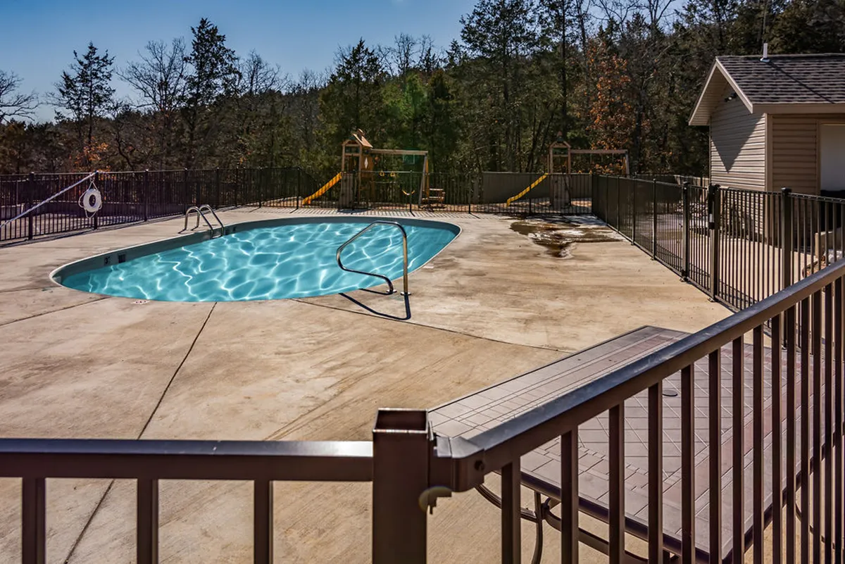 This exterior image features a vibrant swimming pool area with nearby playground equipment, surrounded by trees and a lounge chair. Children are visible playing, and the atmosphere is lively and joyful, evoking a sense of fun and family-friendly relaxation.