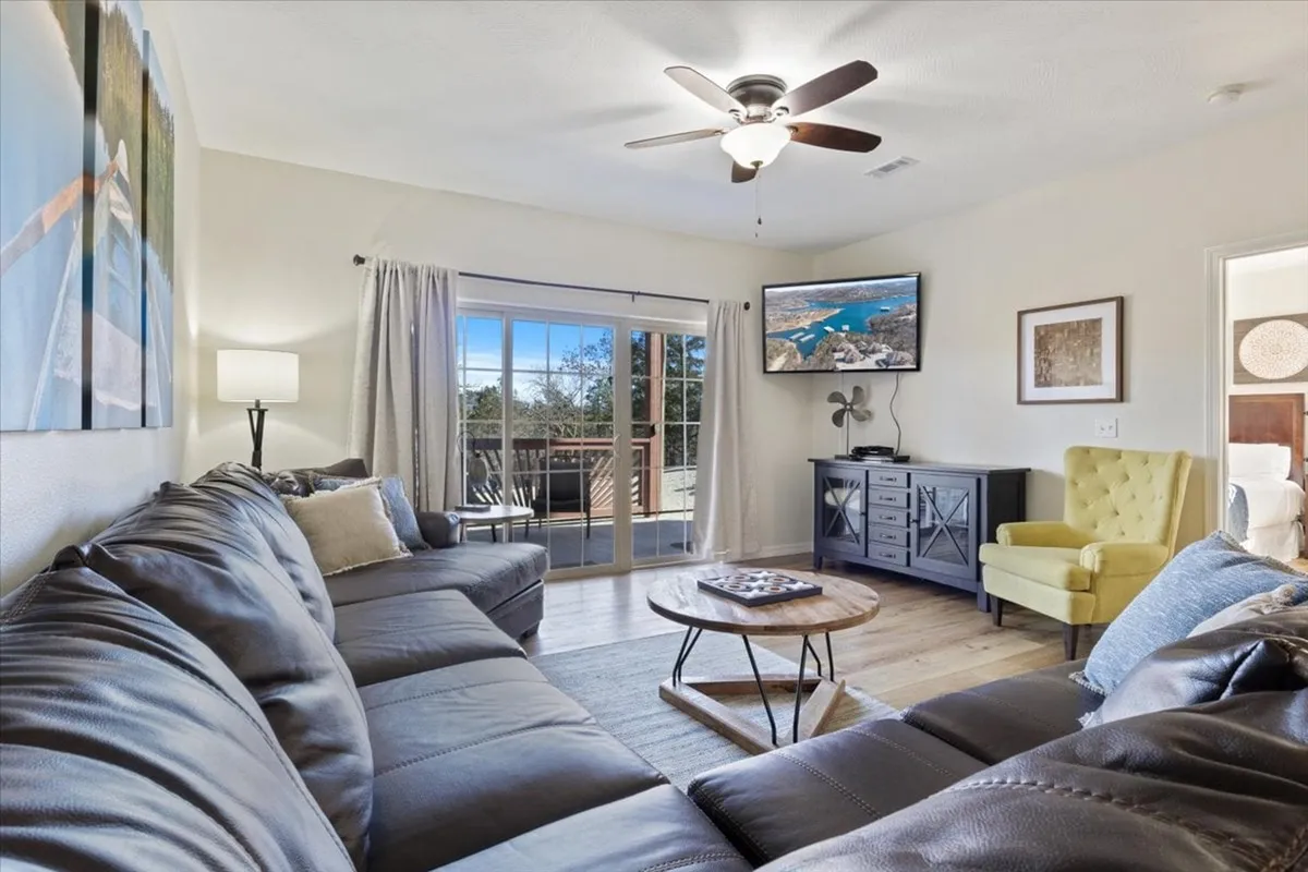 The image showcases a spacious, comfortable living area with a plush leather sofa, a vibrant yellow armchair, a modern coffee table, and a large TV—perfect for relaxing, gathering, or enjoying cozy movie nights. The inviting setup hints at a welcoming space ideal for families or groups.