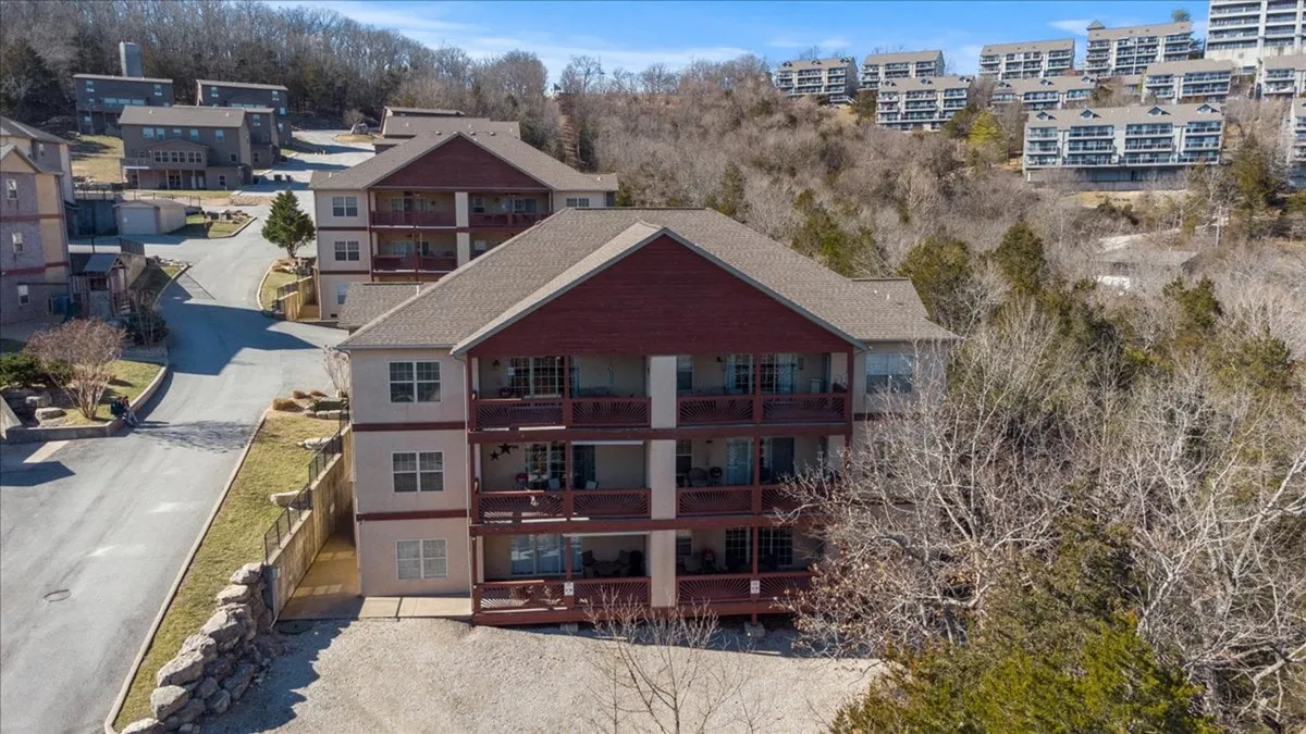A multi-story building nestled among trees, with a roadway leading to the entrance. The natural surroundings and proximity to wooded areas suggest easy access to outdoor activities and walking paths, enhancing the sense of community and connection to nature.